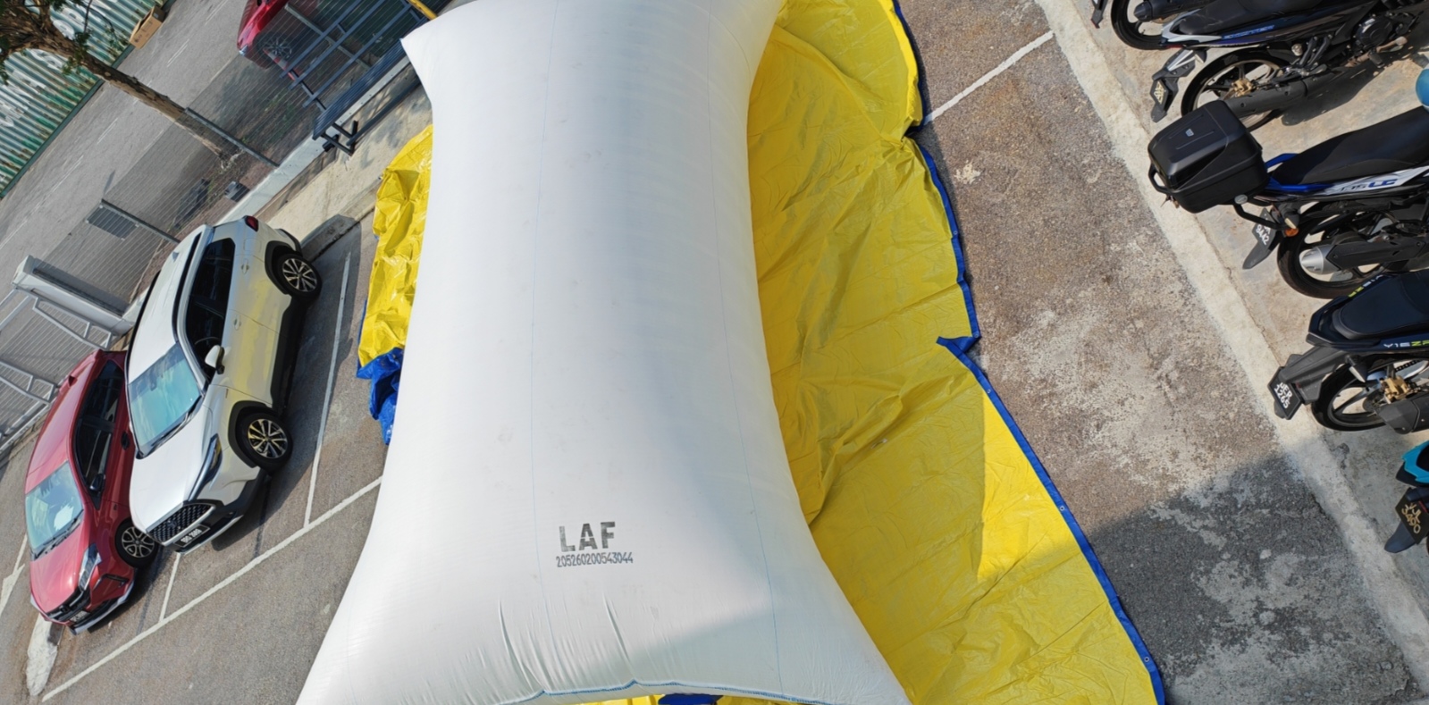 Large inflated flexitank compared with nearby cars and motorcycles